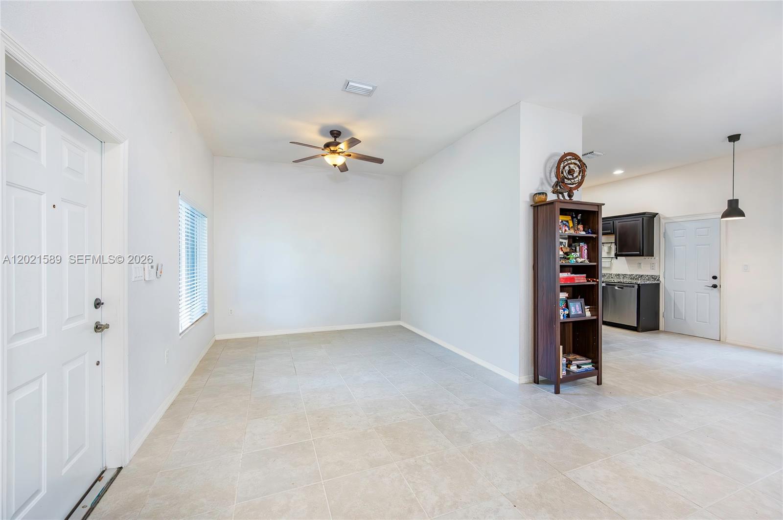 This room features light tile flooring, a ceiling fan, and an open-concept kitchen area — 2343 SE 16th Pl, Homestead FL 33035, HOMESTEAD, FL