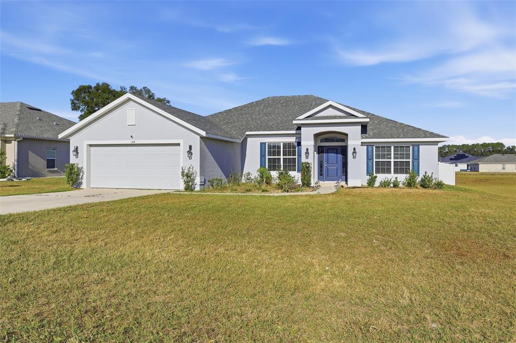 A living room features a grey sofa, a striped armchair, and a wall-mounted television — 9144 SE 47TH COURT ROAD, OCALA, FL