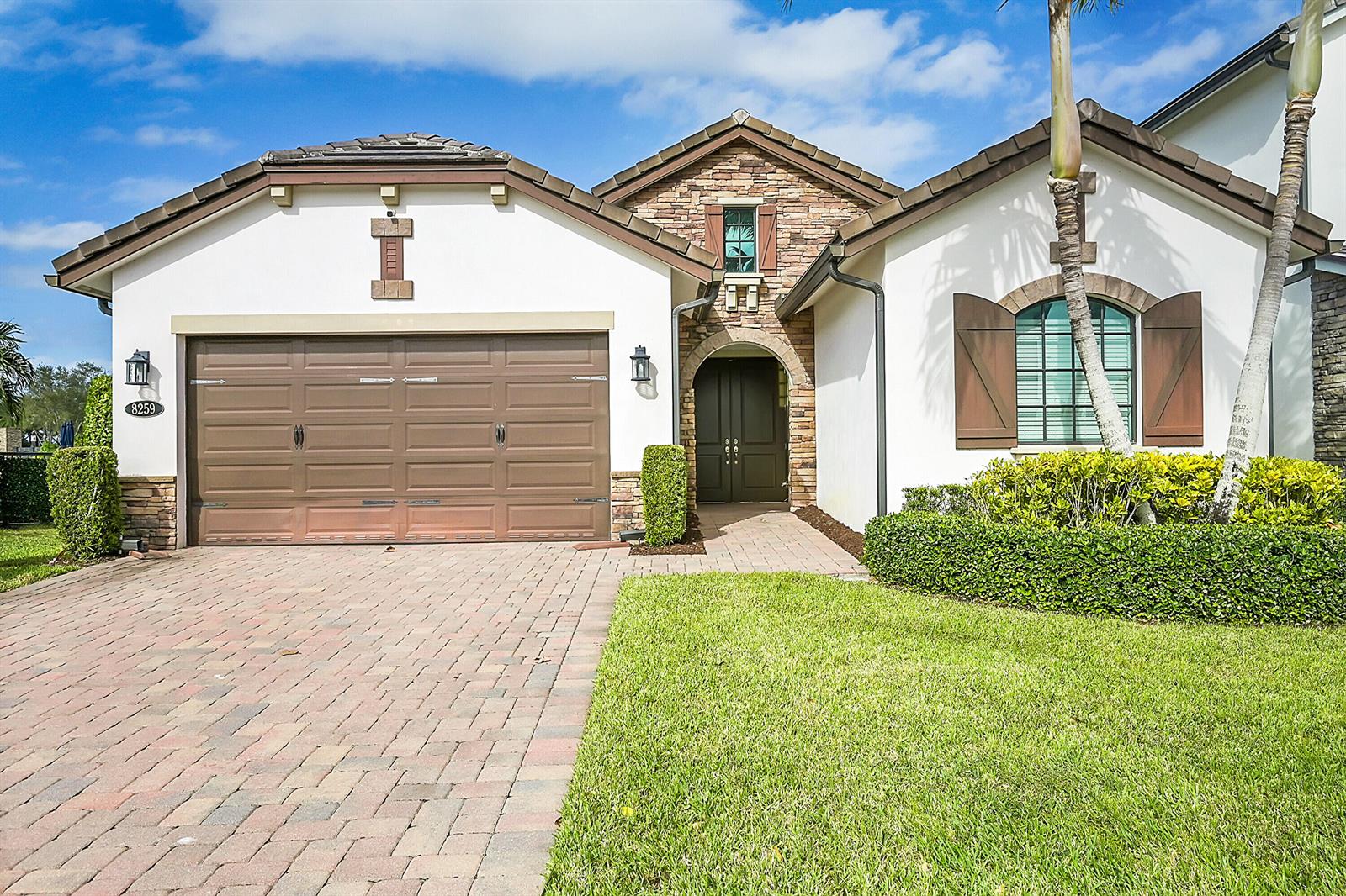 A single-story house with a stone facade, brown garage door, and a brick driveway — 8259 Grand Prix Lane, Boynton Beach FL 33472, BOYNTON BEACH, FL