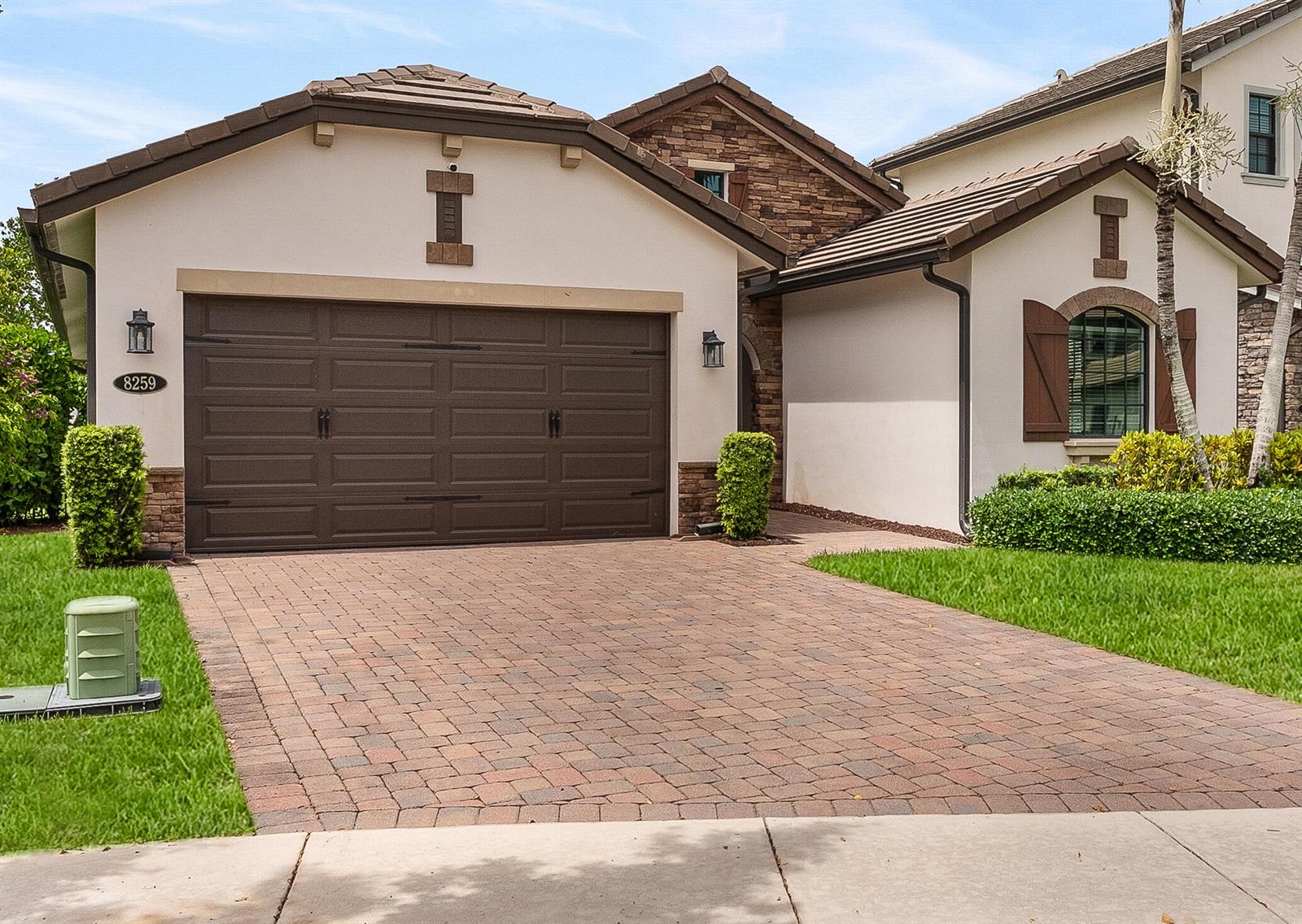 A single-story house exterior features a brown garage door, stone accents, and a paved driveway — 8259 Grand Prix Lane, Boynton Beach FL 33472, BOYNTON BEACH, FL