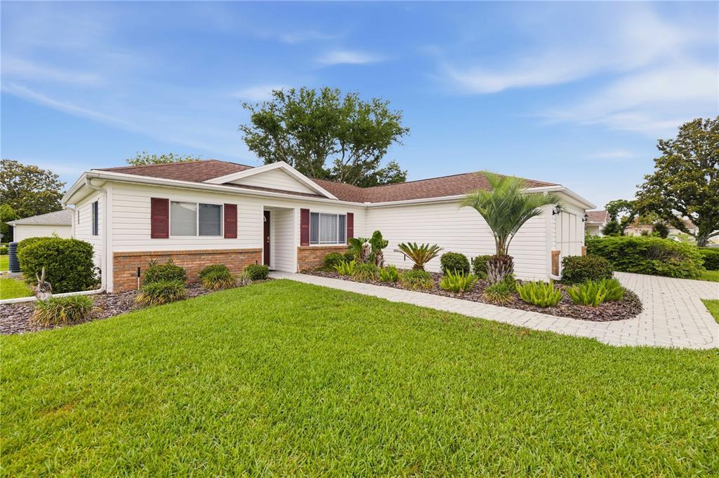 A single-story house with white siding, brick accents, and a paved walkway in the front — 13732 SE 88TH COURT, SUMMERFIELD, FL