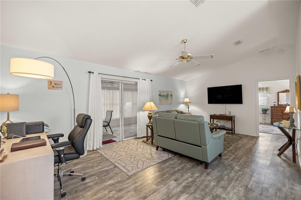 A living room features wood-look flooring, a ceiling fan, a desk area, and sliding glass doors — 13732 SE 88TH COURT, SUMMERFIELD, FL