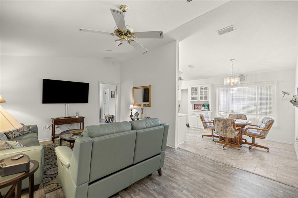 A living room with a light blue sofa leads into a dining area with tile flooring — 13732 SE 88TH COURT, SUMMERFIELD, FL