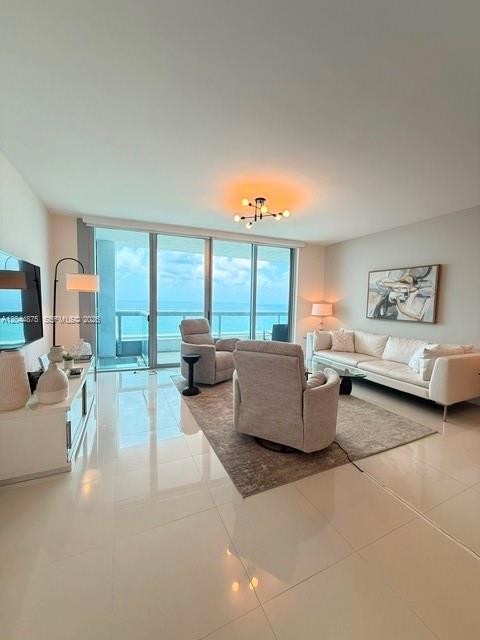 A modern living room features a white sofa, two armchairs, and floor-to-ceiling ocean view windows — 6899 Collins Ave # 2201, Miami Beach FL 33141, MIAMI BEACH, FL