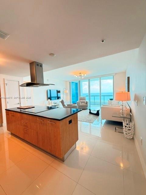A modern kitchen with a wood-toned island overlooks a living area with ocean views — 6899 Collins Ave # 2201, Miami Beach FL 33141, MIAMI BEACH, FL
