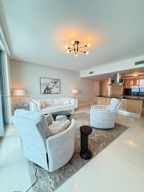 A modern living room features a white sofa, two armchairs, and an open kitchen area — 6899 Collins Ave # 2201, Miami Beach FL 33141, MIAMI BEACH, FL