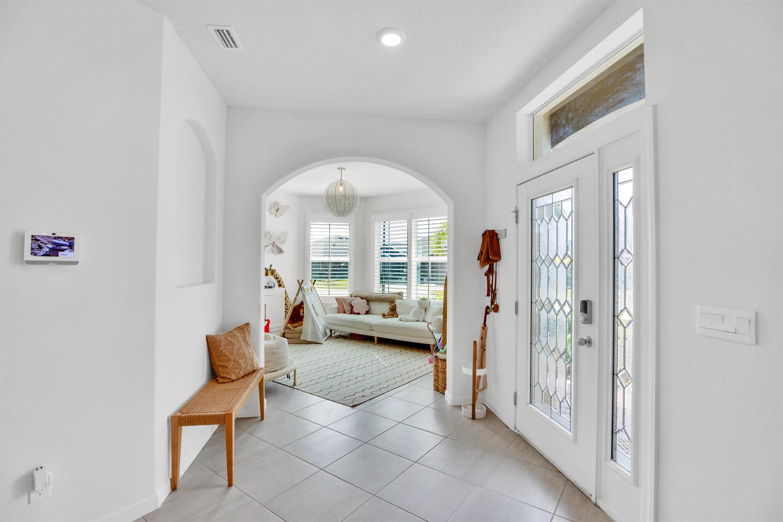 A bright entryway features tile flooring, an arched opening to a living area, and a door — VERO BEACH, FL