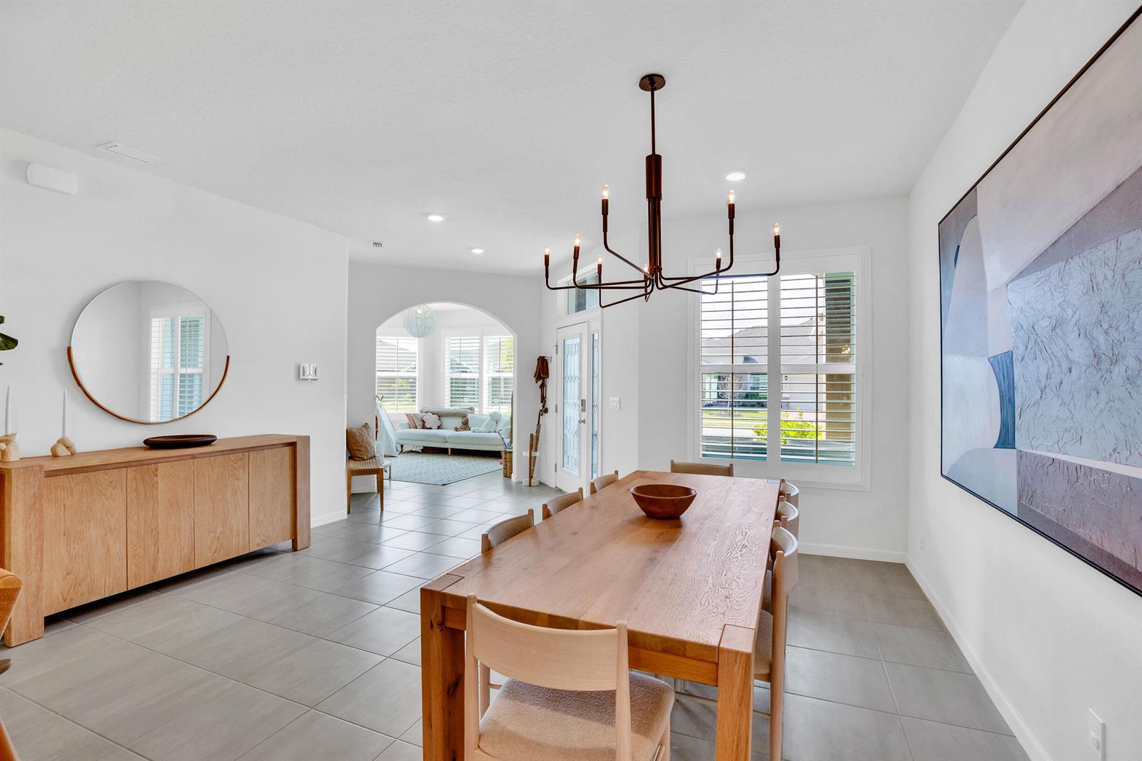 A dining room features a wooden table, a modern chandelier, and a matching sideboard — VERO BEACH, FL