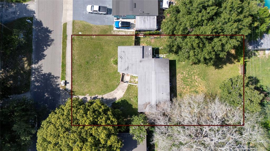 An aerial view shows a house with a flat roof situated on a grassy lot — 4604 ROBBINS AVENUE, ORLANDO, FL