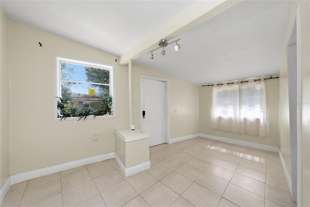 An interior view of a room with beige walls, tile flooring, and a white door — 4604 ROBBINS AVENUE, ORLANDO, FL