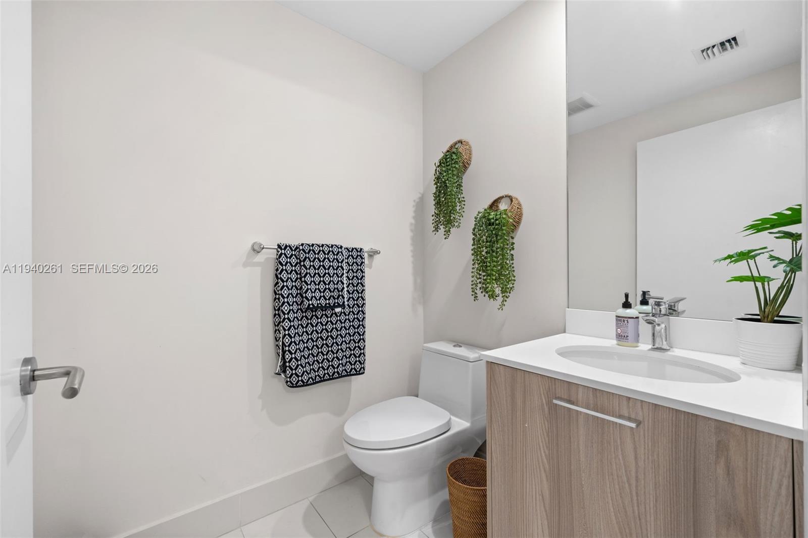 A modern bathroom features a wood-grain vanity, white countertop, white toilet, and hanging wall plants — 501 NE 31st St # 1503, Miami FL 33137, MIAMI, FL