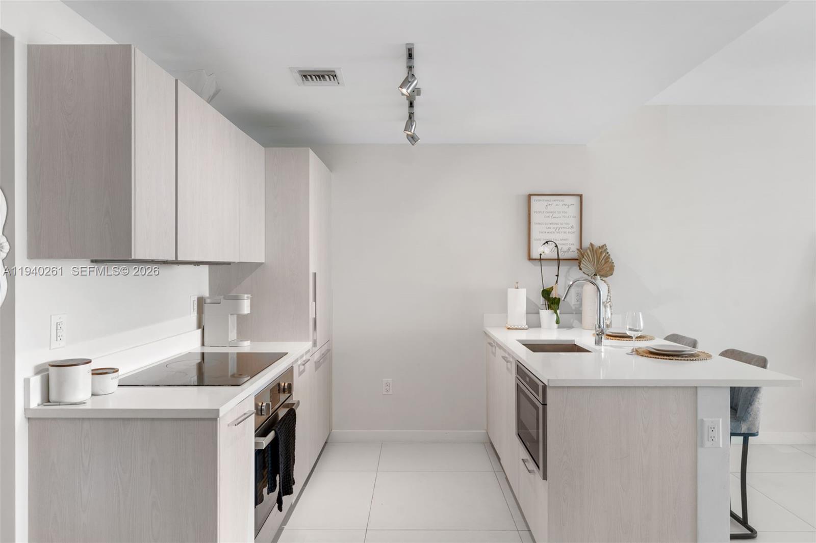 A modern kitchen features light wood cabinetry, white countertops, stainless steel appliances, and tile flooring — 501 NE 31st St # 1503, Miami FL 33137, MIAMI, FL