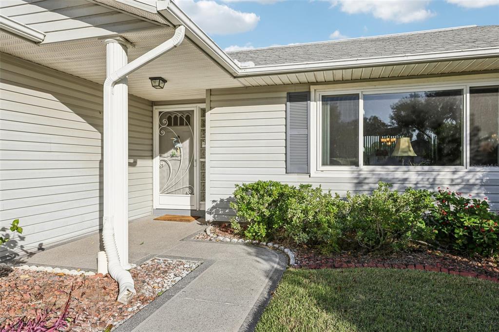 The exterior of a house features light gray siding, a concrete walkway, and a front door — 26209 NEWCOMBE CIRCLE, LEESBURG, FL