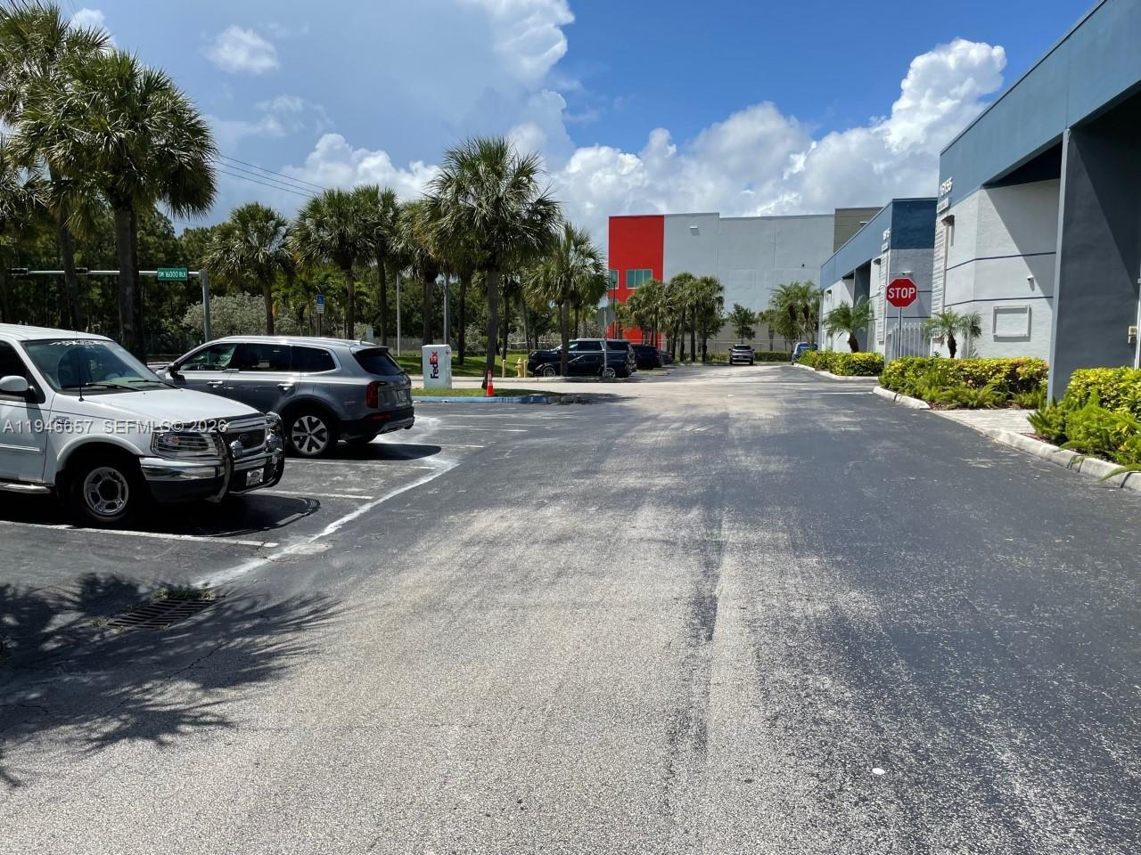 An outdoor parking lot with palm trees, parked vehicles, and a commercial building exterior — 16155 SW 117th Ave # B2, Miami FL 33177, MIAMI, FL