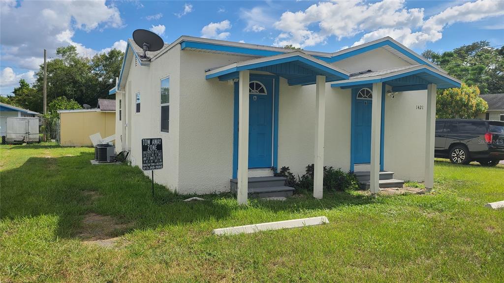 A single-story duplex with white stucco walls, blue trim, and two separate front entrances — 1421 E 108TH AVENUE UNIT A, TAMPA, FL
