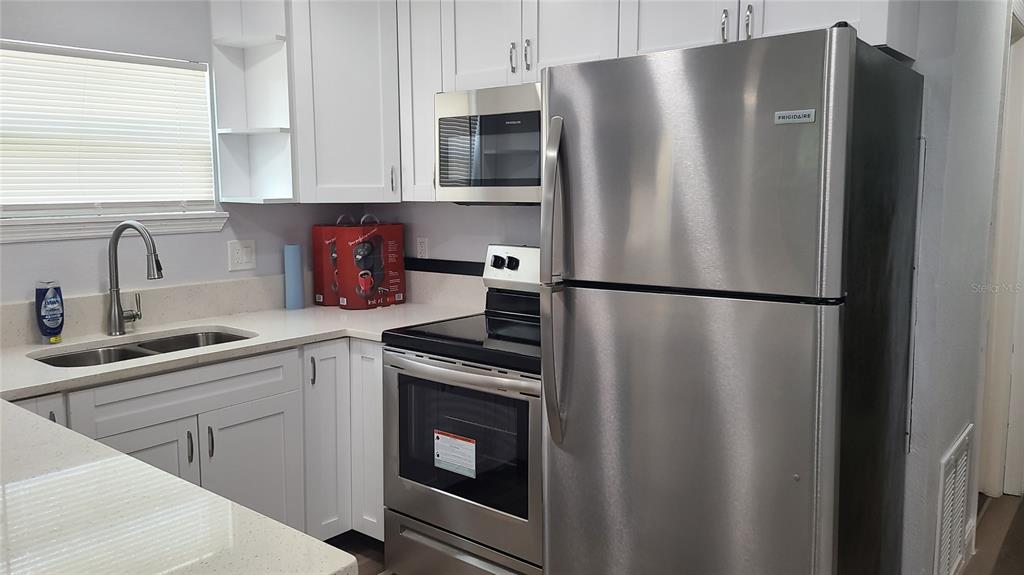 A kitchen features white cabinets, stainless steel appliances, and light-colored countertops — 1421 E 108TH AVENUE UNIT A, TAMPA, FL
