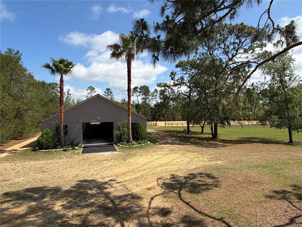 A gray detached garage sits on a sandy lot with palm trees and a fence — 4251 NE 136TH AVENUE, WILLISTON, FL