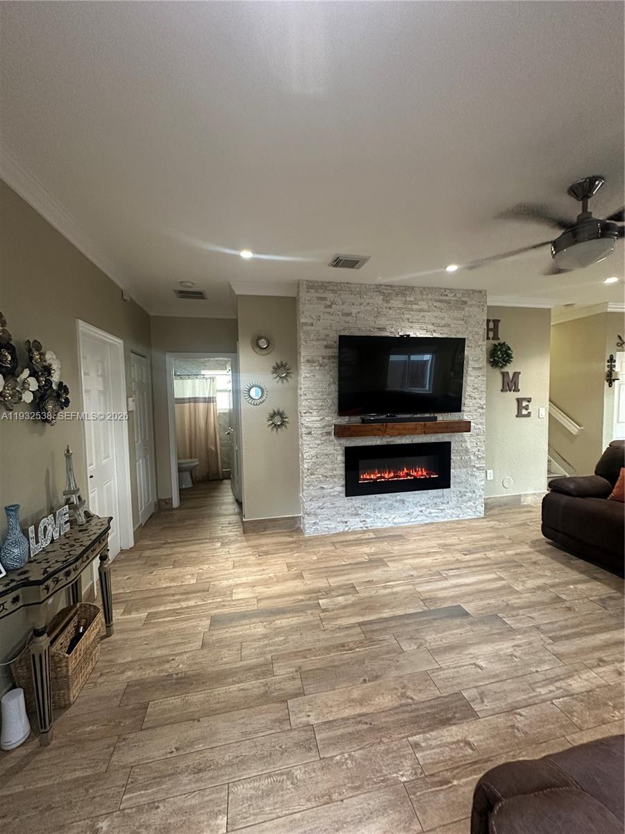 A living room features a stone fireplace with a mounted television and wood-look tile flooring — 3134 NE 3rd Dr, Homestead FL 33033, HOMESTEAD, FL