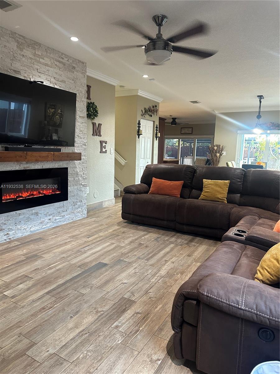 A living room features a stone fireplace, a large television, and a brown sectional sofa — 3134 NE 3rd Dr, Homestead FL 33033, HOMESTEAD, FL