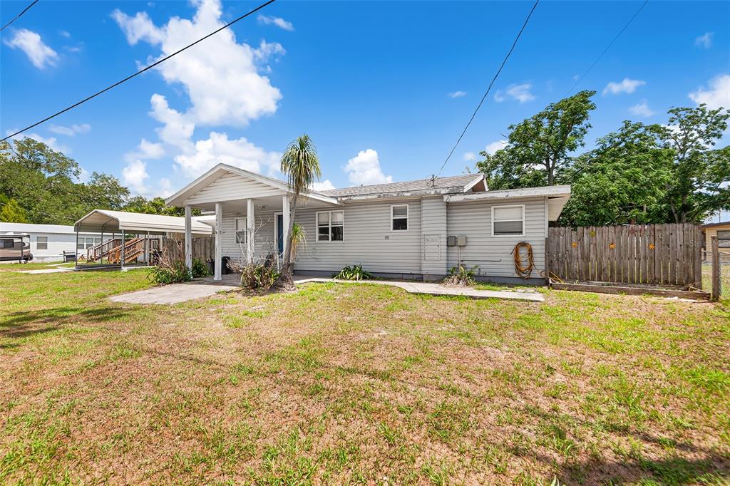 A single-story house with light gray siding, a covered porch, and a wooden privacy fence — 39014 KIRKLAND DRIVE, ZEPHYRHILLS, FL
