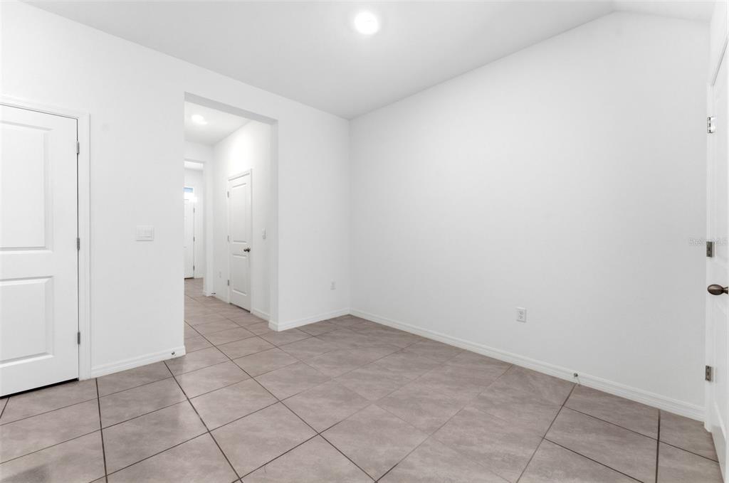 A bright, empty room with white walls, tiled floors, and multiple interior doors — 16632 GROTTO STEAM PLACE, WIMAUMA, FL