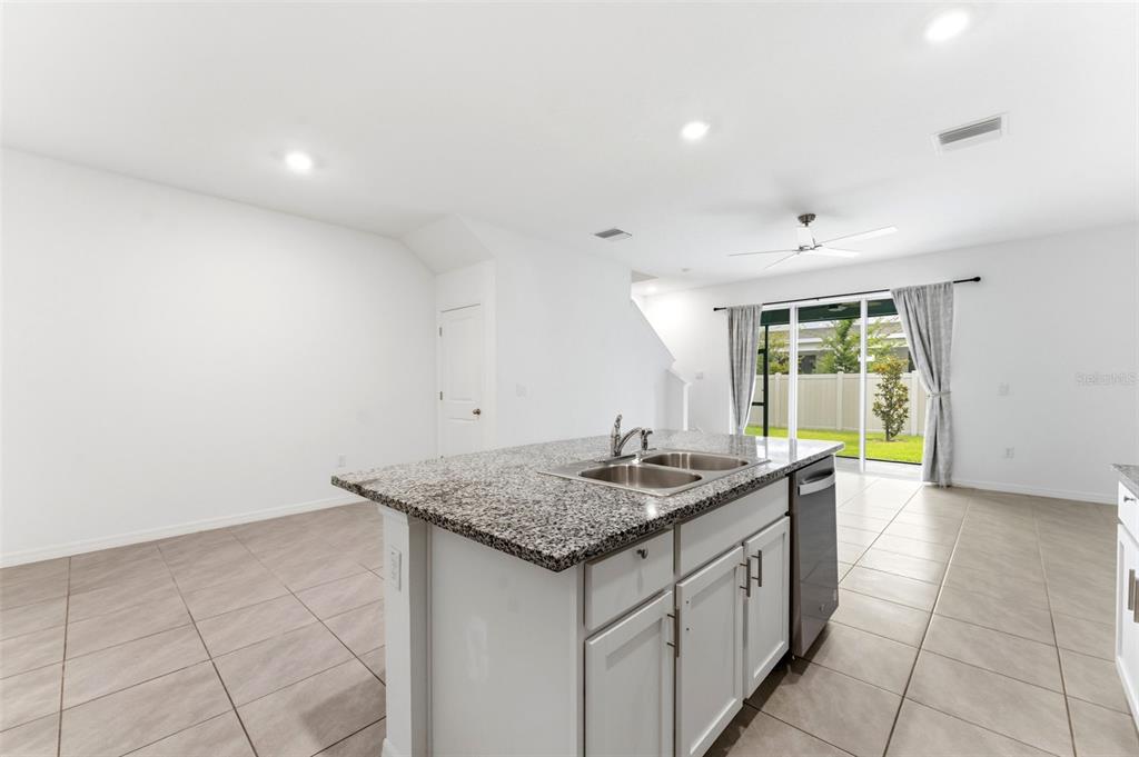 A kitchen island with a granite countertop sits in a room with tile flooring — 16632 GROTTO STEAM PLACE, WIMAUMA, FL