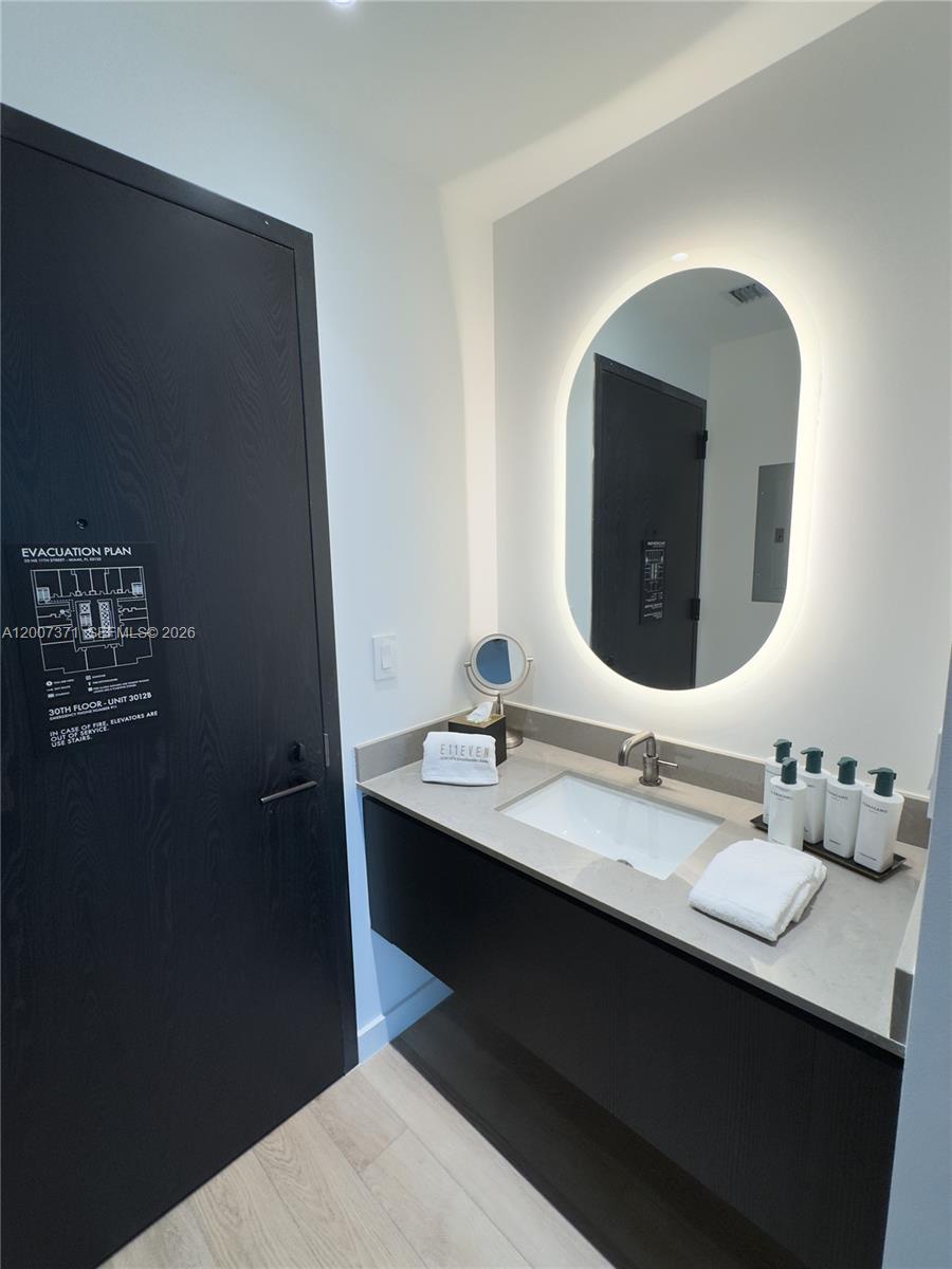 A modern bathroom features a floating vanity, a backlit oval mirror, and a dark door — 20 NE 11th St # 3012B, Miami FL 33132, MIAMI, FL