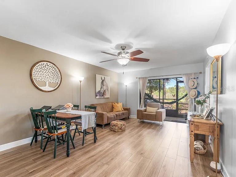 A living and dining room with wood-look flooring, a ceiling fan, and a screened porch — 109 MEADOW LANE, OLDSMAR, FL