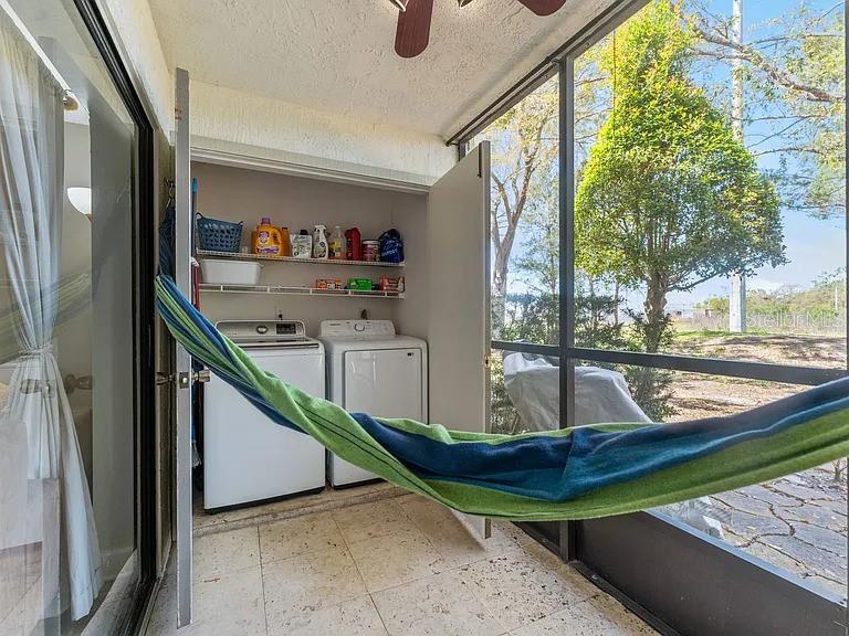 A screened-in porch features a laundry closet with two machines and a hanging hammock — 109 MEADOW LANE, OLDSMAR, FL