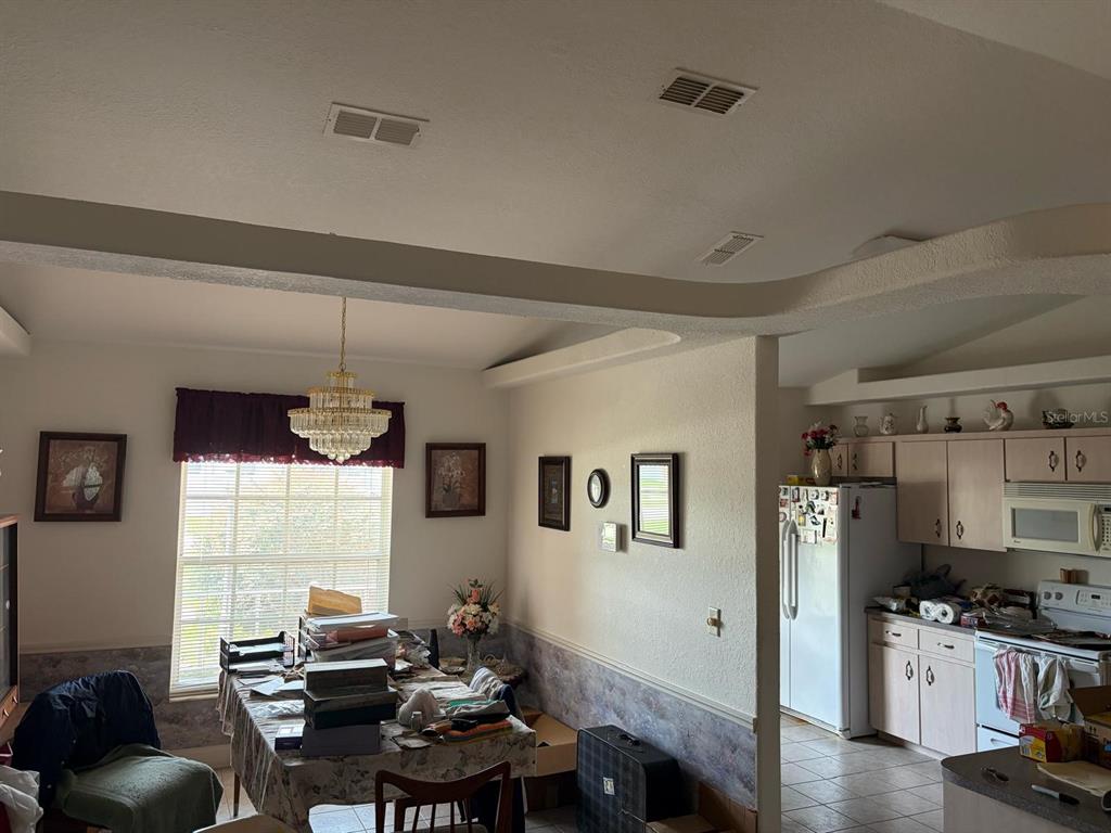 A dining area with a crystal chandelier opens into a kitchen with light-colored cabinets — 126 BRIGHTON CIRCLE, AUBURNDALE, FL
