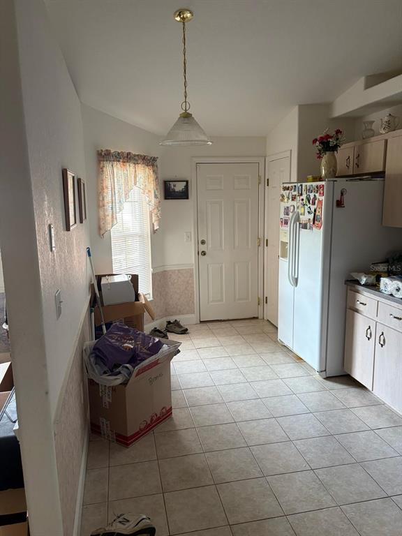 A kitchen features tile flooring, a white refrigerator, a pendant light, and a side door — 126 BRIGHTON CIRCLE, AUBURNDALE, FL