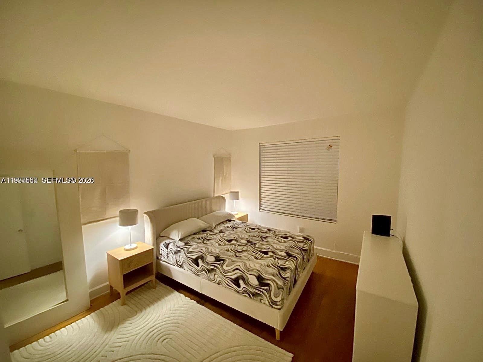 A bedroom features a bed with a patterned comforter, two nightstands, and a white dresser — 605 Euclid Ave # 103, Miami Beach FL 33139, MIAMI BEACH, FL