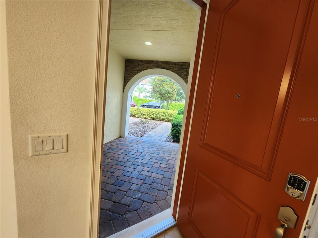 An open orange door reveals a view of a stone-paved entryway and arched walkway — 9805 WINNINGTON STREET, ORLANDO, FL