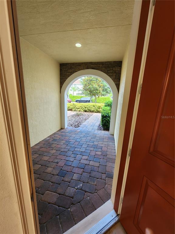 A view from an open doorway looking out onto a paved entryway with an arched opening — 9805 WINNINGTON STREET, ORLANDO, FL