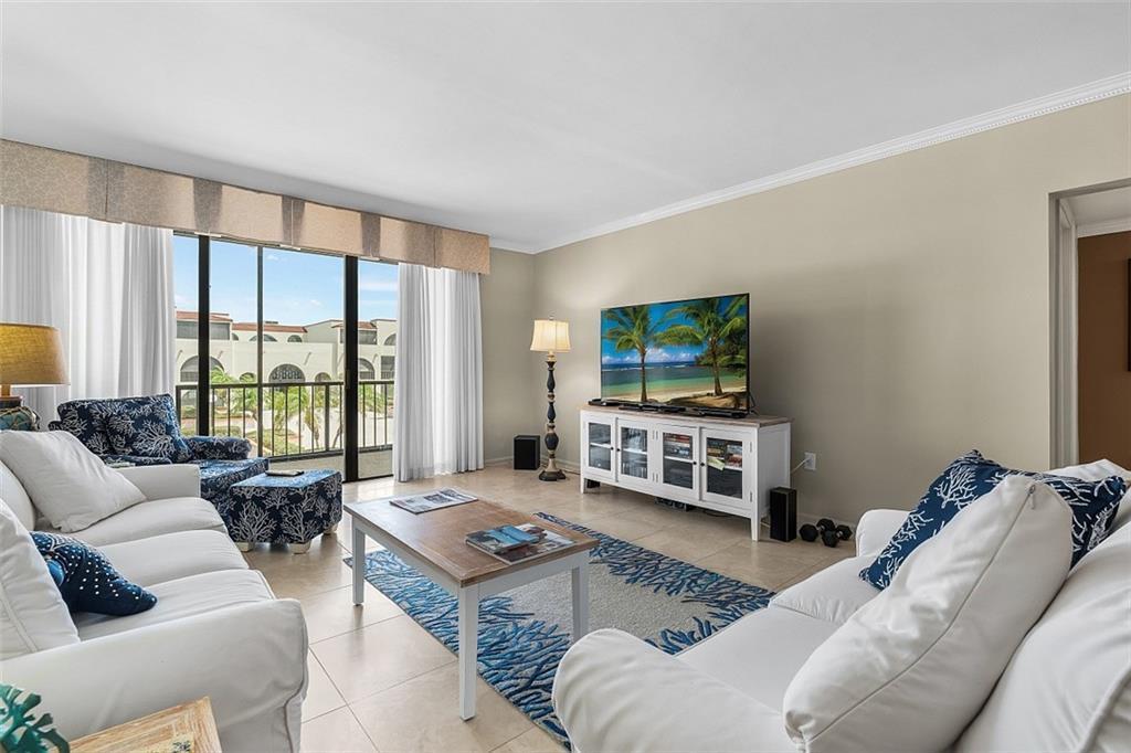 A living room features white sofas, a blue patterned rug, and a television on a console — VERO BEACH, FL