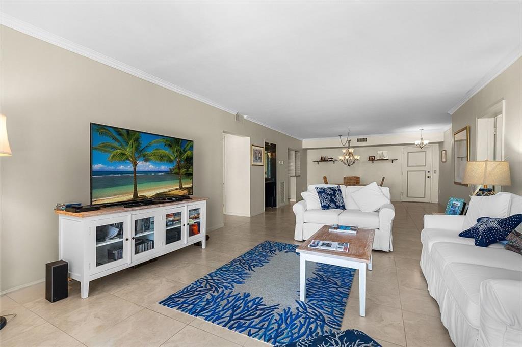 A living room features white furniture, a blue coral-patterned rug, and a large television — VERO BEACH, FL