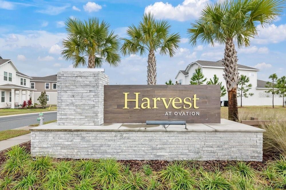 A stone monument sign for Harvest at Ovation stands in front of houses and palm trees — 15026 SUMMER HARVEST STREET, WINTER GARDEN, FL