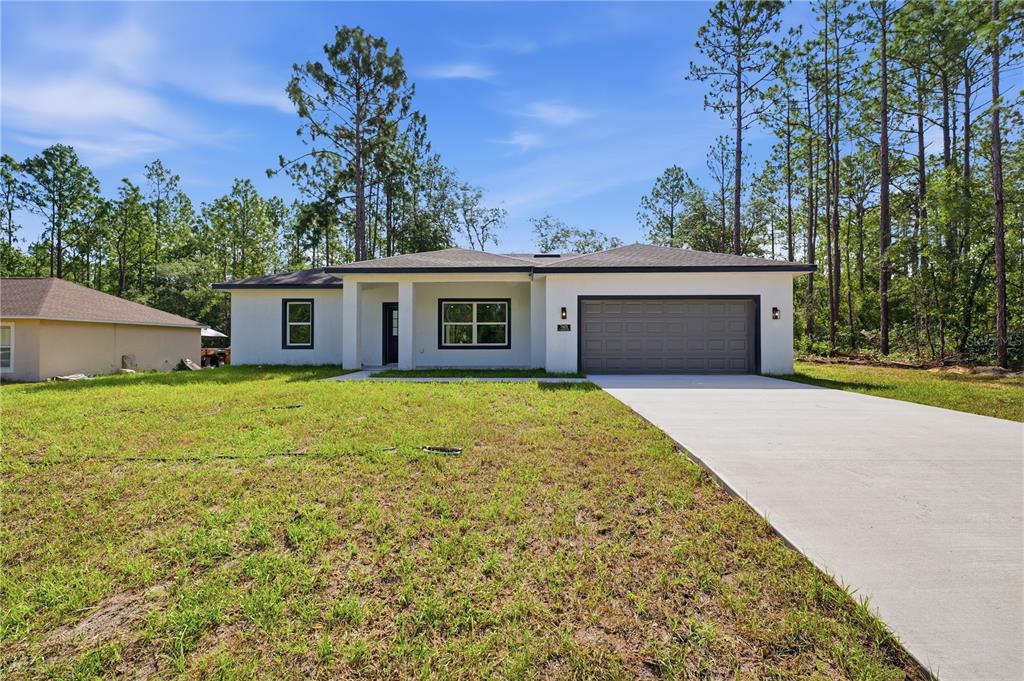 A single-story house with a white exterior, dark trim, and a two-car garage — 7605 N SANTOS DRIVE, CITRUS SPRINGS, FL