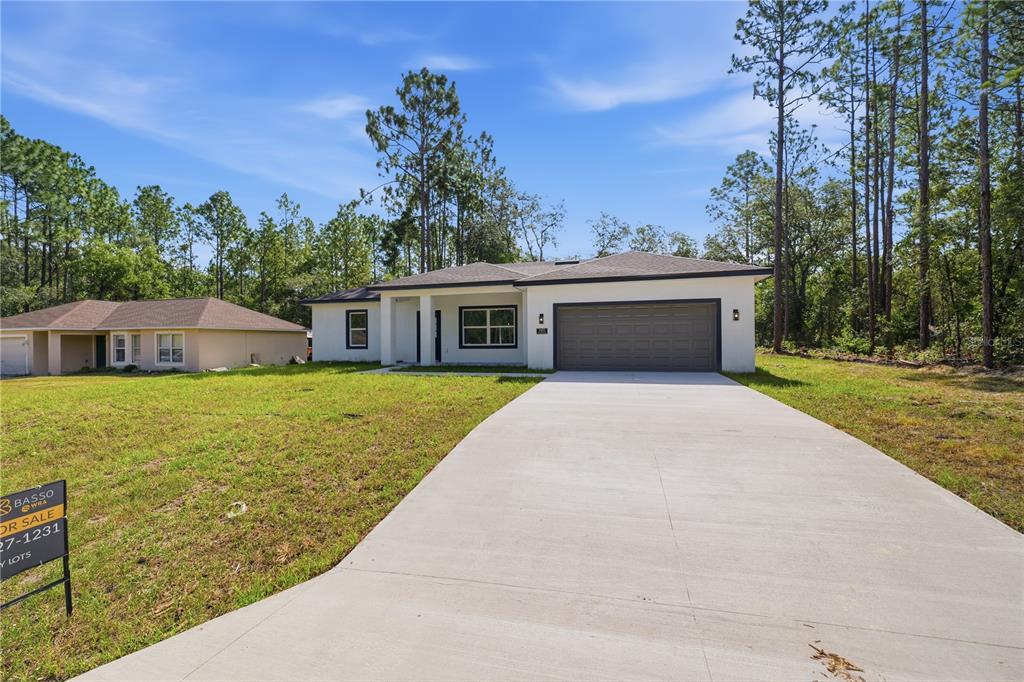 A modern, single-story white house with a gray garage stands on a grassy lot — 7605 N SANTOS DRIVE, CITRUS SPRINGS, FL