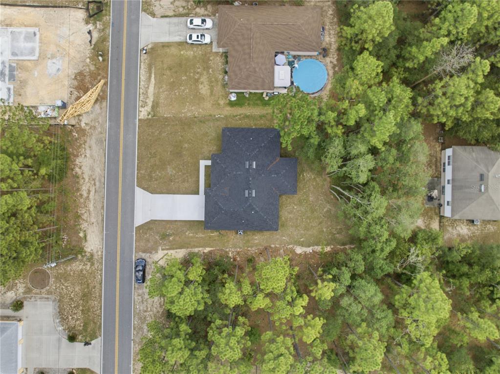 An aerial view shows a house with a dark roof, a concrete driveway, and trees — 7605 N SANTOS DRIVE, CITRUS SPRINGS, FL