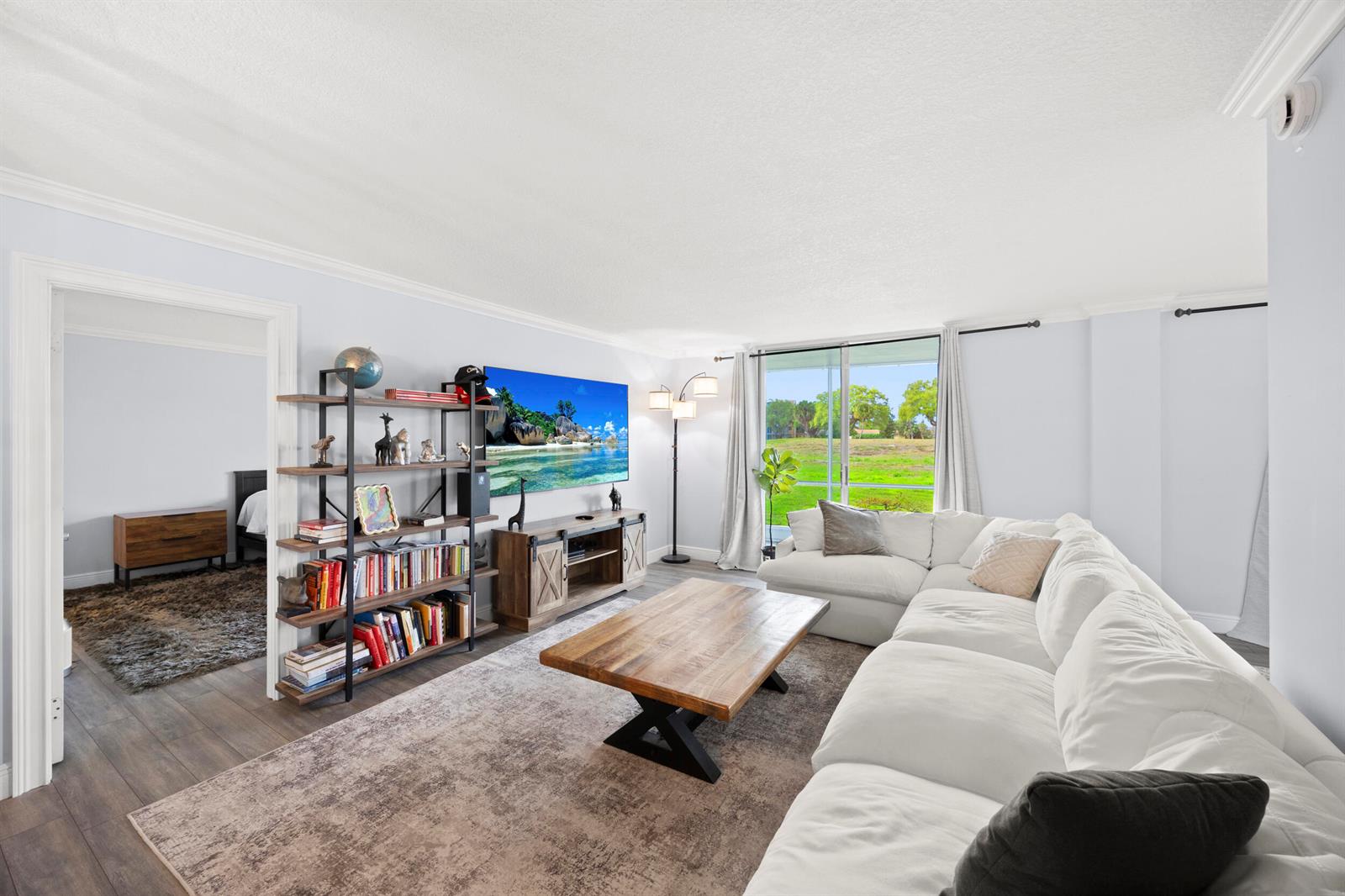 A living room features a white sectional sofa, wood coffee table, and a large television — 5301 NW 2nd Avenue # 1010, Boca Raton FL 33487, BOCA RATON, FL