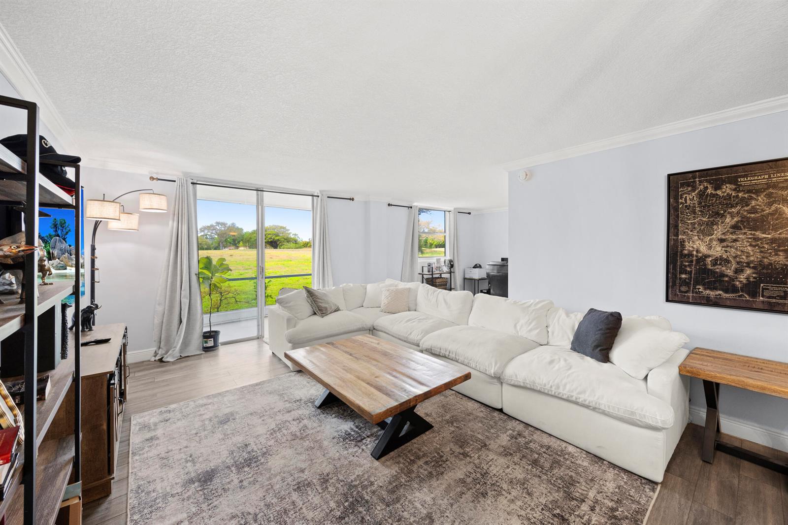 A living room features a white sectional sofa, wooden coffee table, and sliding glass doors — 5301 NW 2nd Avenue # 1010, Boca Raton FL 33487, BOCA RATON, FL
