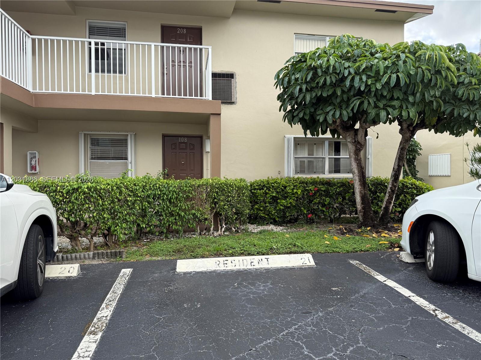 A two-story apartment building exterior features brown doors, white railings, and designated parking spaces — 600 NW 77th Ave # 108, Margate FL 33063, MARGATE, FL