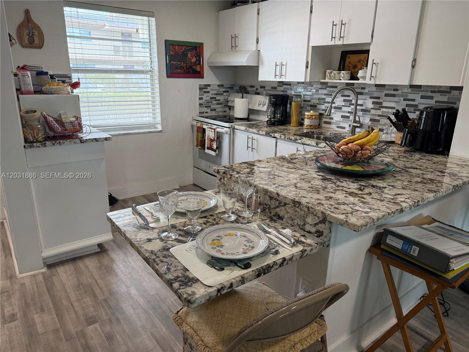 A kitchen features white cabinets, granite countertops, a breakfast bar, and a dining area — 600 NW 77th Ave # 108, Margate FL 33063, MARGATE, FL