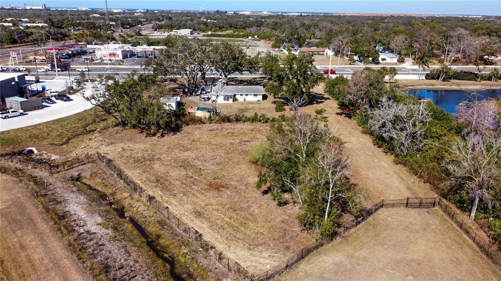 An aerial view shows a fenced, grassy lot with trees, a house, and a pond — 2519 MOCCASIN WALLOW ROAD, PALMETTO, FL