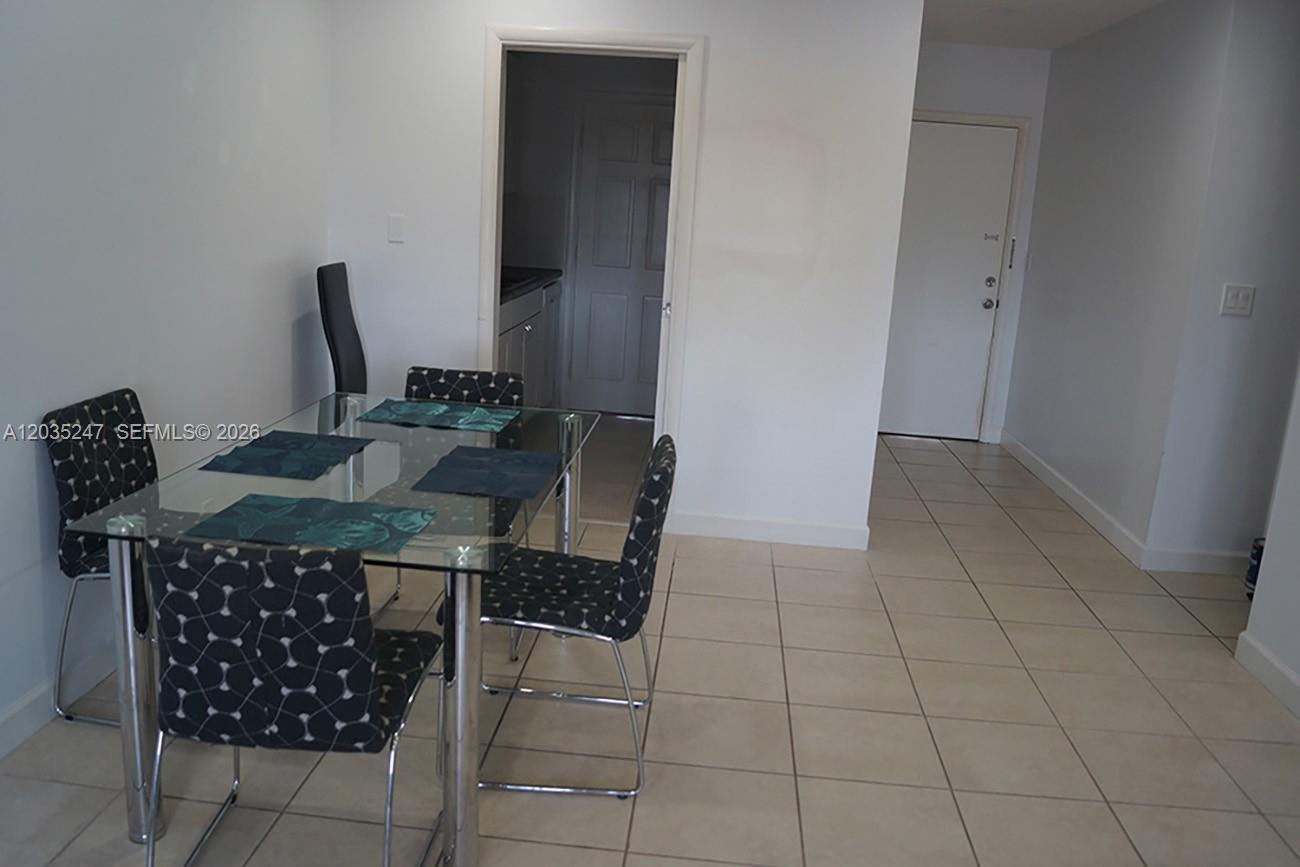 A dining area features a glass-topped table with patterned chairs on a tiled floor — 1250 E Sample Rd # 303, Pompano Beach FL 33064, POMPANO BEACH, FL