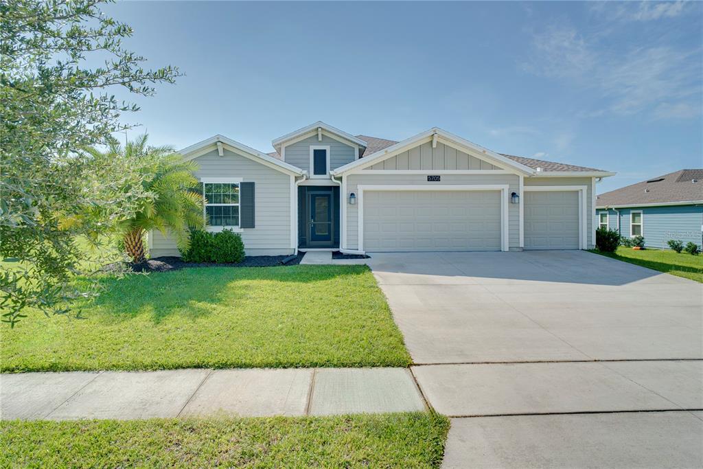 A single-story house with light gray siding, a three-car garage, and a front lawn — 5705 ALENLON WAY, MOUNT DORA, FL
