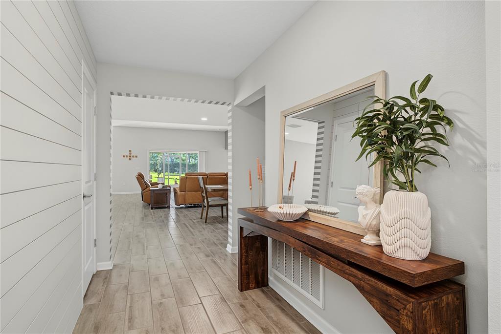 A hallway features wood-look tile flooring, a shiplap wall, and a wooden console table with decor — 5705 ALENLON WAY, MOUNT DORA, FL