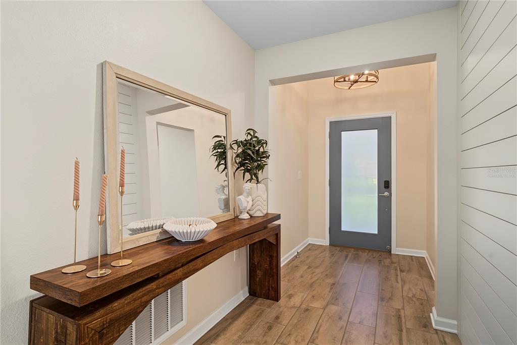 An entryway features a wood console table, a large mirror, and a gray front door — 5705 ALENLON WAY, MOUNT DORA, FL
