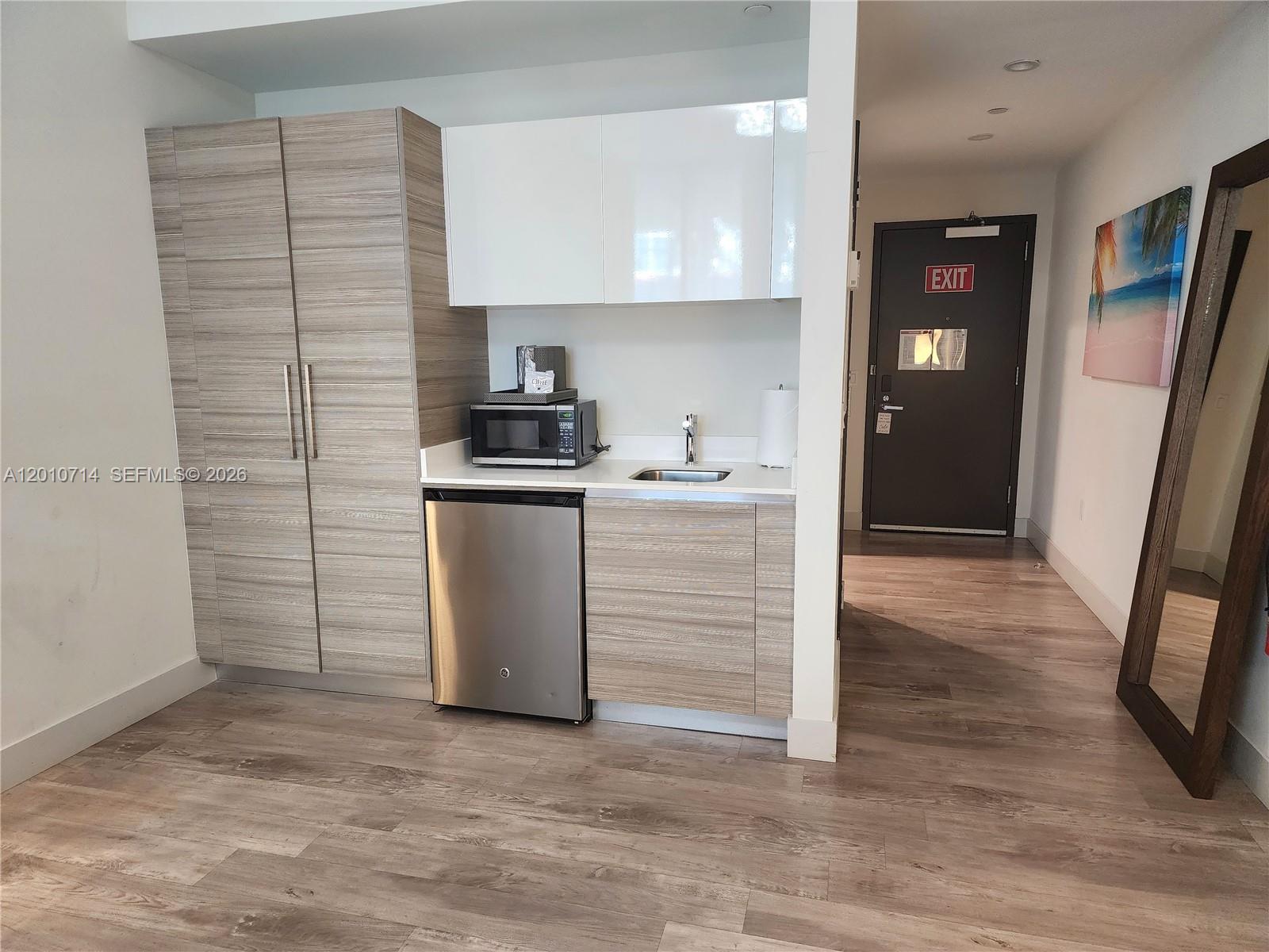 A kitchenette features wood-grain cabinetry, white upper cabinets, a microwave, and a small refrigerator — 777 N Ocean Dr # S207, Hollywood FL 33019, HOLLYWOOD, FL